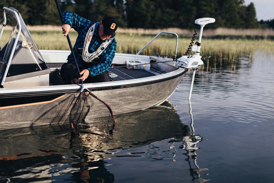 Kalastusopas Jani Ollikainen nostaa haukea keulasähkömoottorilla varustettuun Buster-kalastusveneeseen