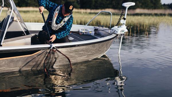 Kalastusopas Jani Ollikainen nostaa haukea keulasähkömoottorilla varustettuun Buster-kalastusveneeseen